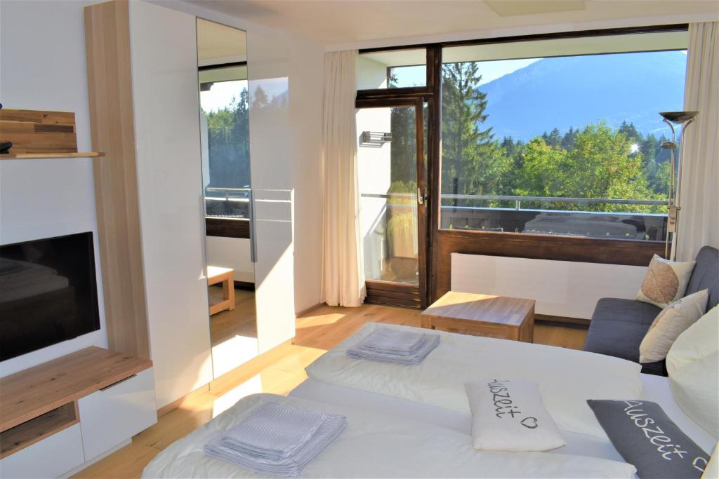 a living room with a white bed and a large window at Apartment d´Auszeit in Bad Goisern