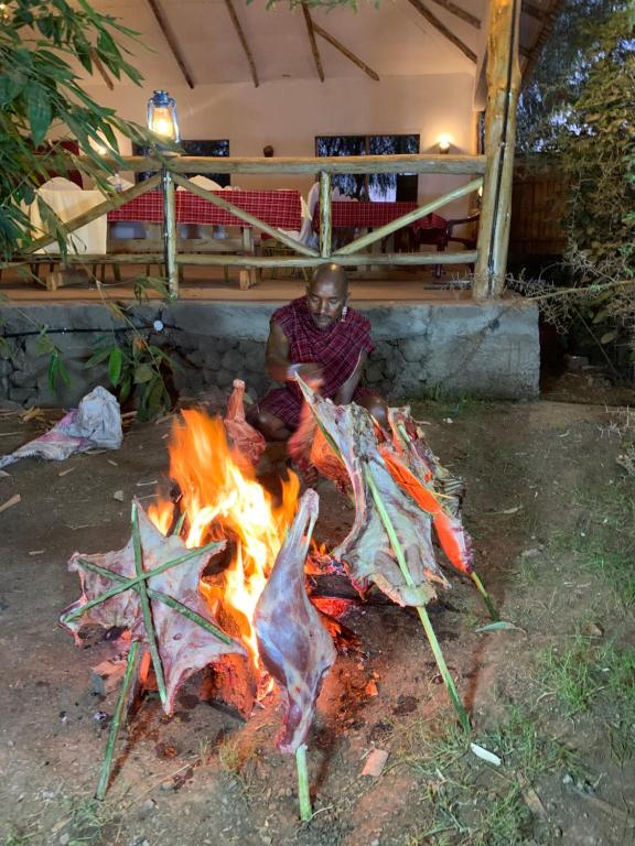 a man is sitting around a camp fire at Hillstone Safari Lodge in Kimana