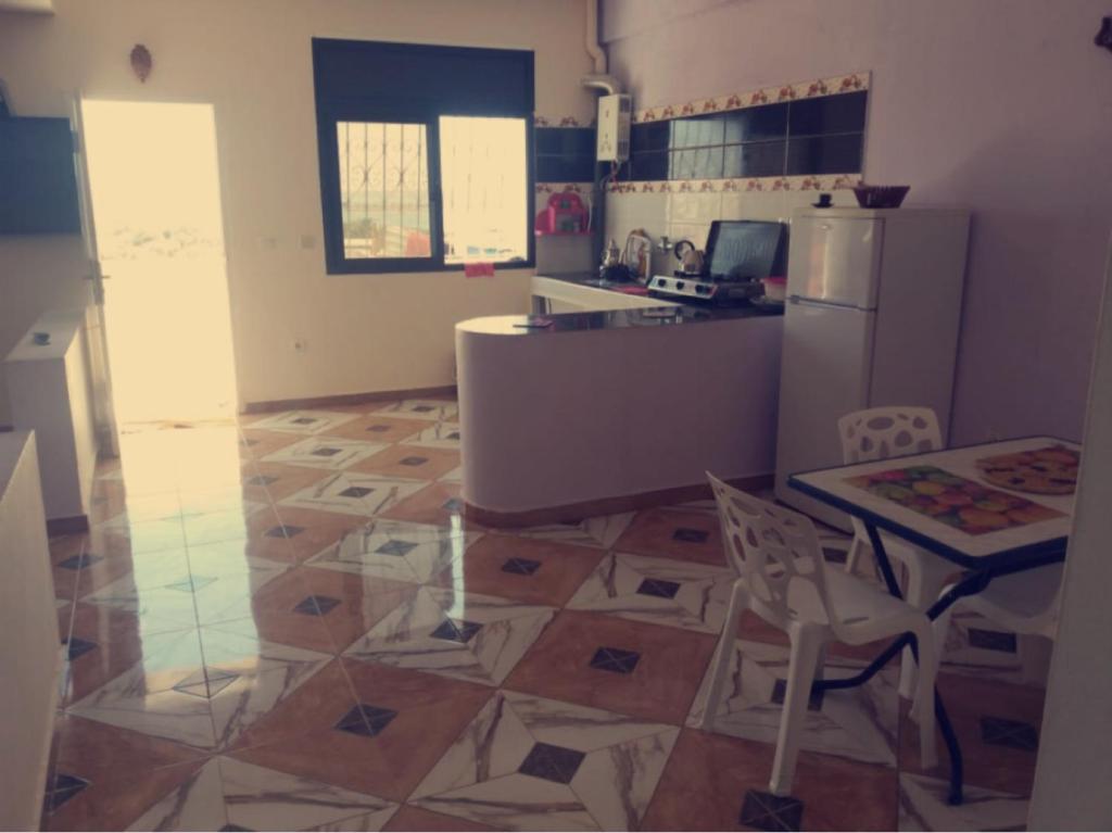 a kitchen with a table and a refrigerator at Blue meadow in Moulay Bousselham