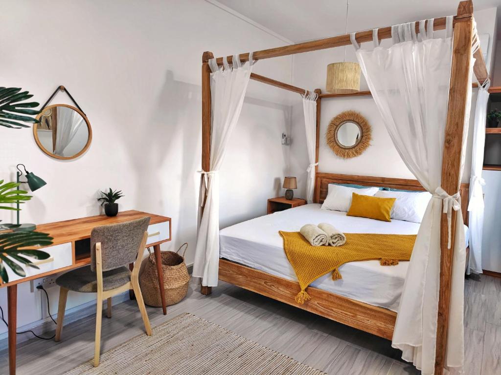 a bedroom with a canopy bed with a desk and a desk at Villa le Dodo - GBH in Grand Baie