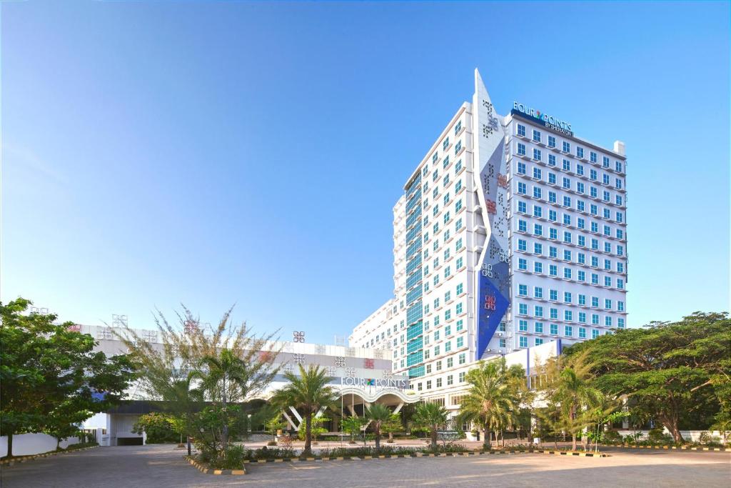 a tall building with palm trees in front of it at Four Points by Sheraton Makassar in Makassar