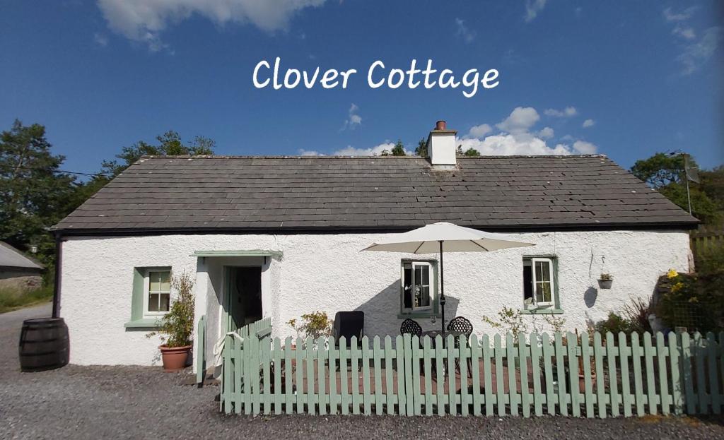 斯萊戈的住宿－Clover Cottage，白色的房子,配有白色的围栏和雨伞