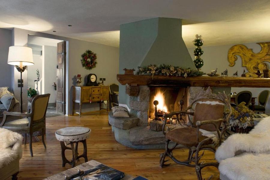a living room with a fireplace with a couch and chairs at Locanda La Brenva - Estella Hotel Collection in Courmayeur