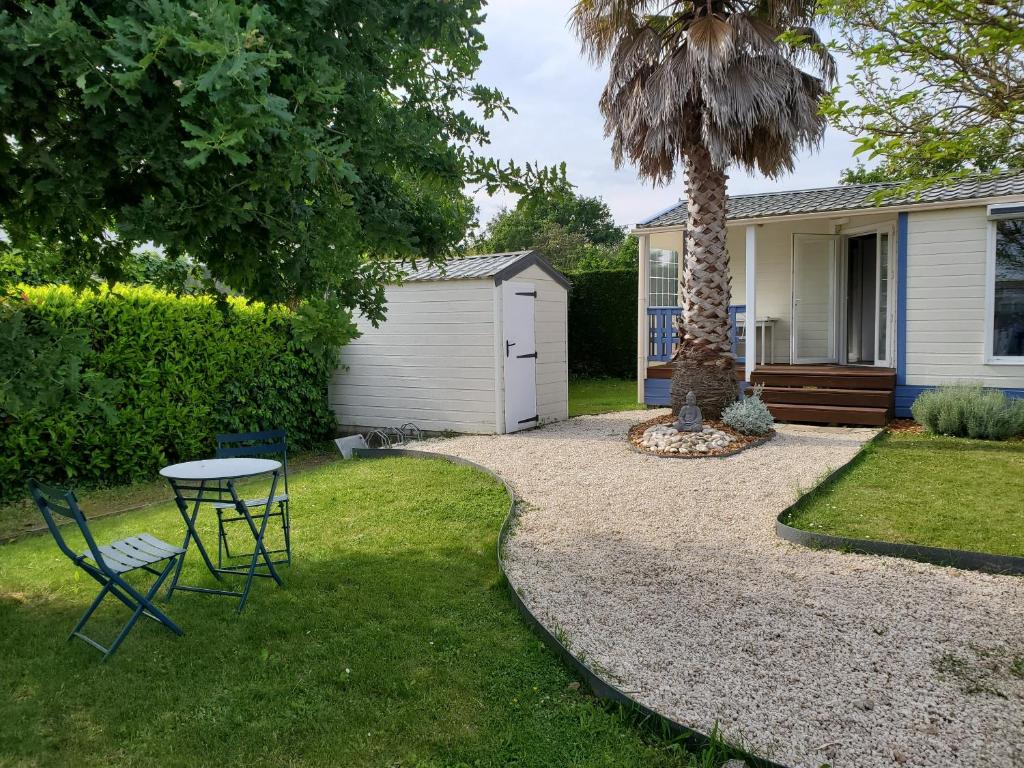a patio with a table and chairs and a palm tree at Mobil Home 5 pers 1 Km de l'Océan in Talmont