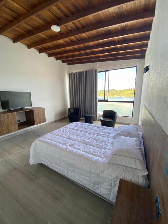 ein Schlafzimmer mit einem großen Bett mit 2 Stühlen und einem TV in der Unterkunft TERRA DI ACQUA in El Peñol