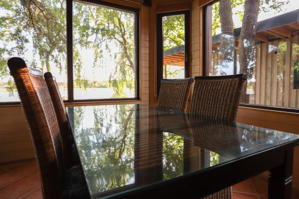 uma mesa de vidro e cadeiras num quarto com janelas em Szum Muzy Ruś Mała em Ostróda