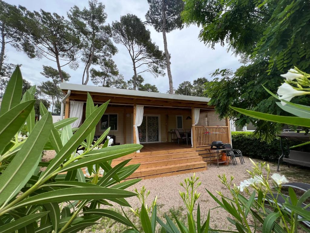 a tiny house with a deck in a garden at LunaBay Biograd Mobile Home in Biograd na Moru
