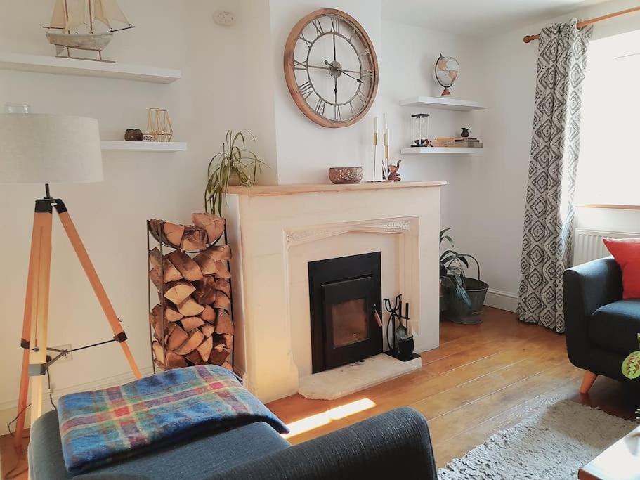 a living room with a fireplace and a clock on the wall at Converted Barn in Bath in Bath
