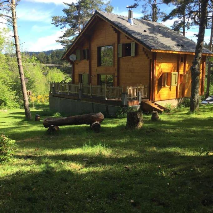 une cabane en rondins avec une terrasse couverte sur une pelouse dans l'établissement Chalet le Brame en Cevennes, à Camprieu