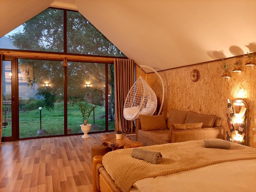 a bedroom with a bed and a couch and a large window at Kazbegi cottages qabarjina in Kazbegi