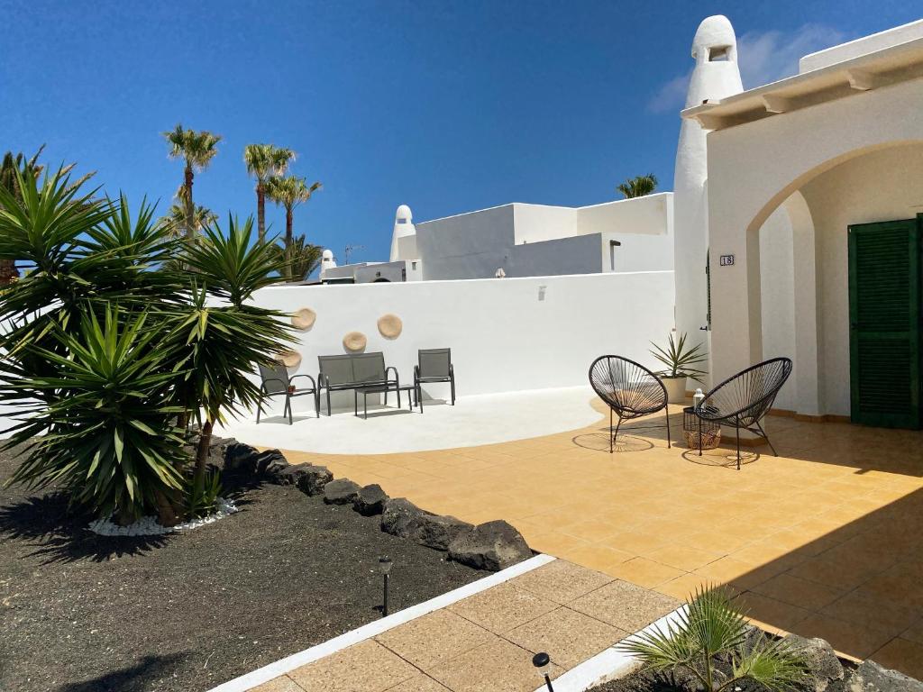 a patio with chairs and a white building at Villa Maranvi in Playa Blanca