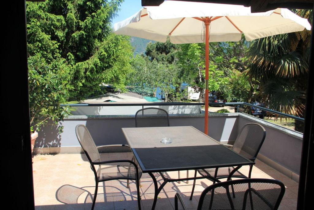 einen Tisch und Stühle mit Sonnenschirm auf dem Balkon in der Unterkunft Veranda Beach Apartment in Pianello Del Lario