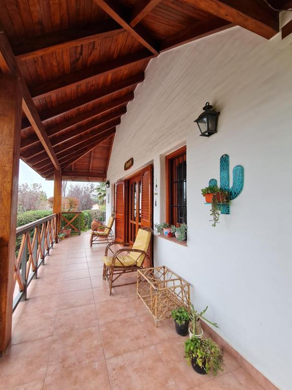 um alpendre de uma casa com cadeiras e um cacto em Cabanas Las Pencas, HOSTERIA em Mina Clavero