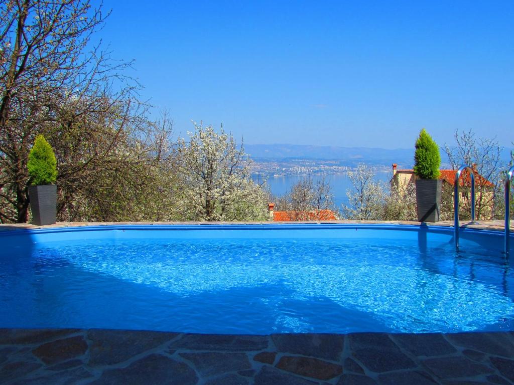 een blauw zwembad met uitzicht op het water bij House Aronia in Lovran