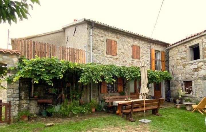 a stone house with a bench and an umbrella at Pri kovačih, Istra autentica in Movraž