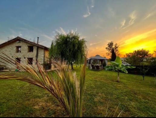 Sagasta Rural - Oviedo في أوفِييذو: منزل في حقل مع غروب الشمس في الخلفية