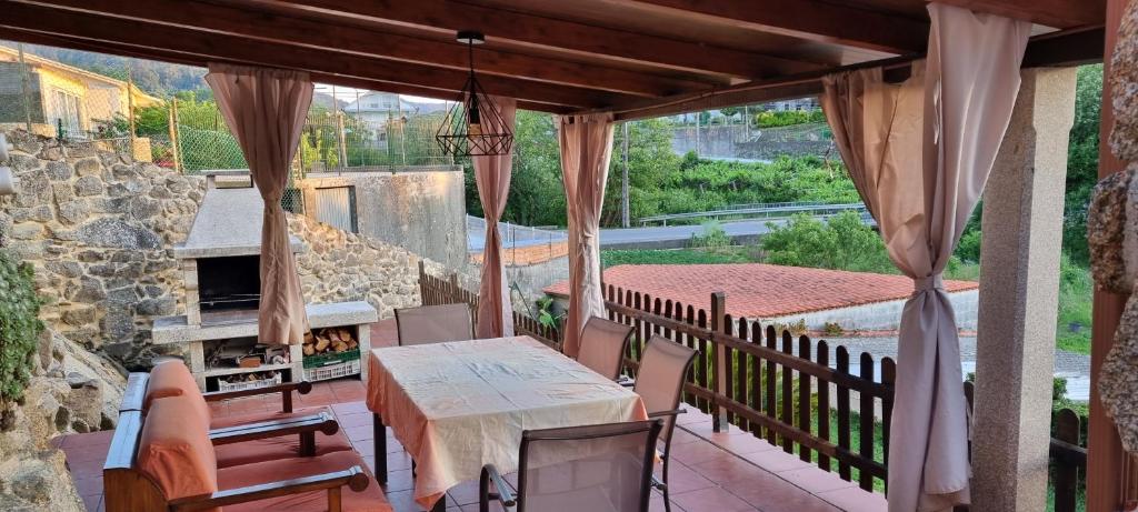a patio with a table and chairs and a stone fireplace at A CASA DE ABAIXO LOIRA in Marín