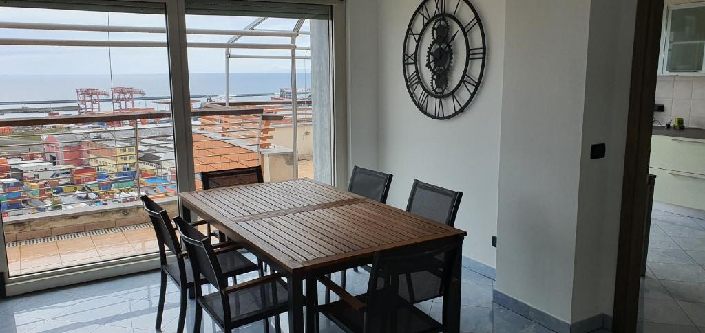 熱那亞的住宿－Attico con Vista su Genova，餐桌、椅子和墙上的时钟