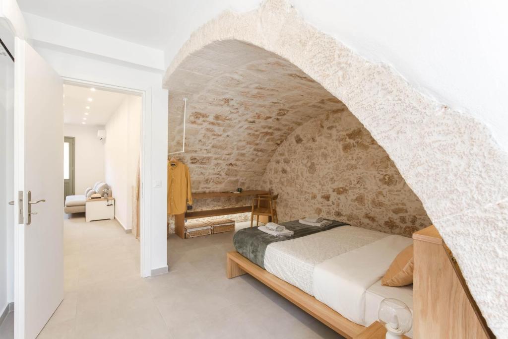 um quarto com uma parede de pedra e uma cama. em Lindas Convent Garden Home 1 em Chania Town