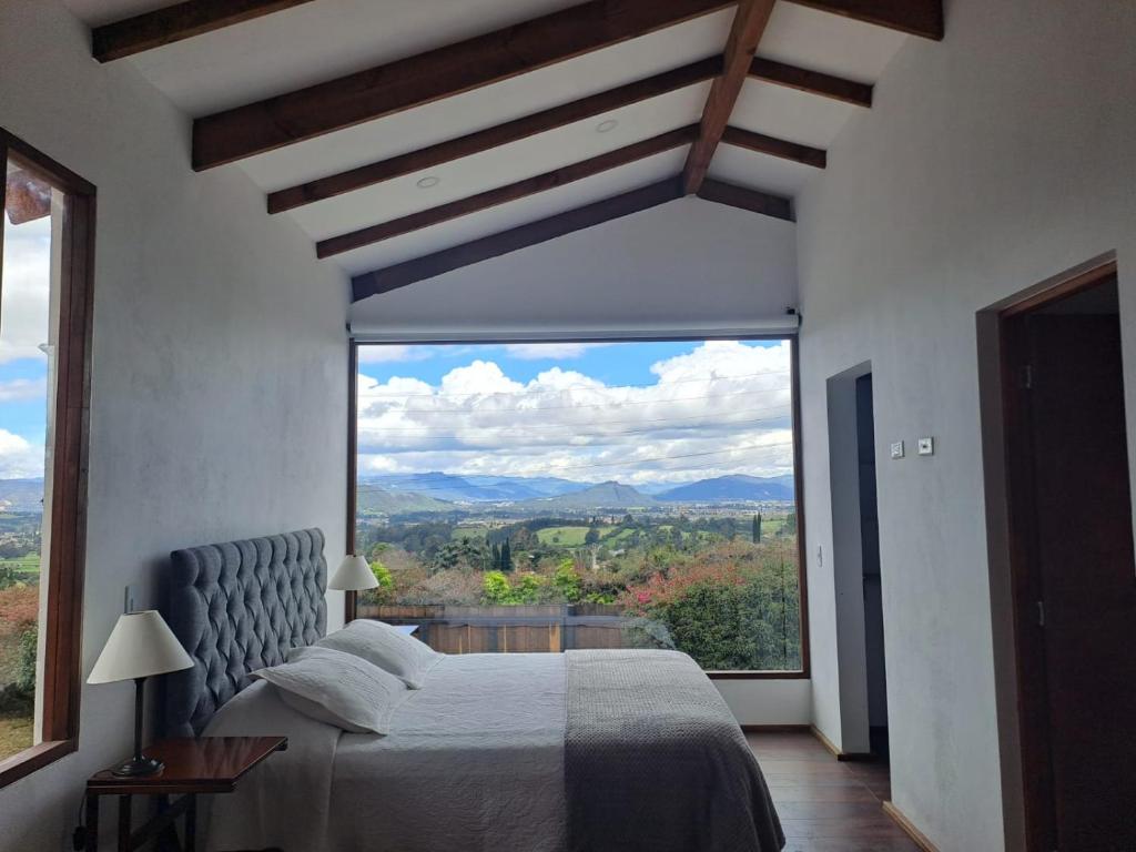 a bedroom with a bed and a large window at Despierte con la naturaleza in Cogua