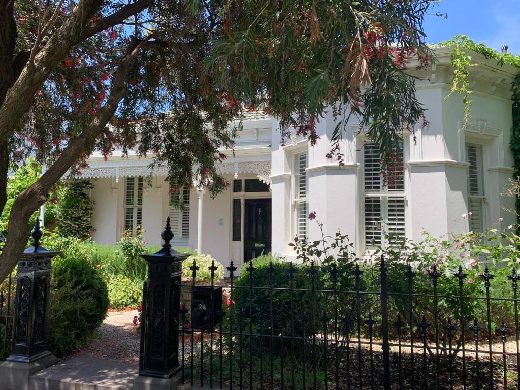 una casa blanca con una valla y un árbol en A Majestic Victorian Private Rear Access Quarters en Melbourne