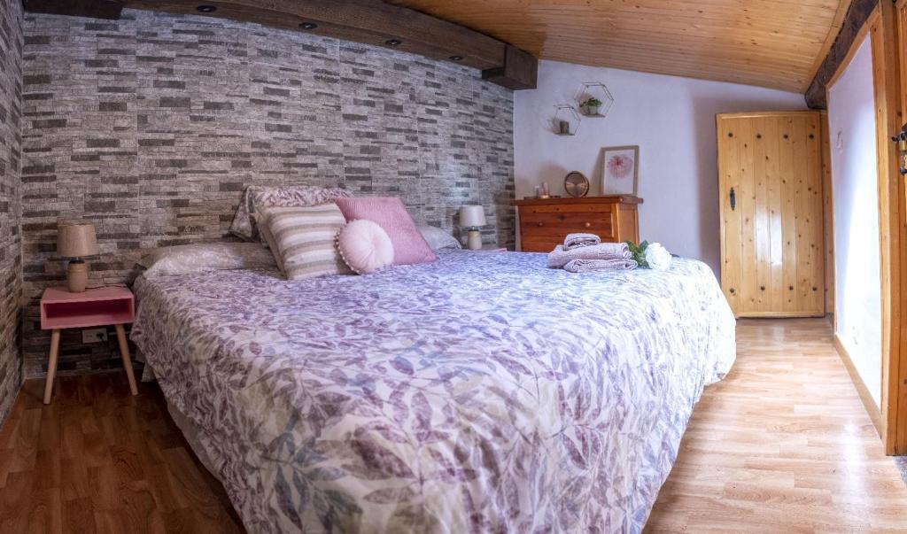 ein Schlafzimmer mit einem großen Bett und einer Ziegelwand in der Unterkunft Casa Rural El Burrito de Gredos in Pedro Bernardo