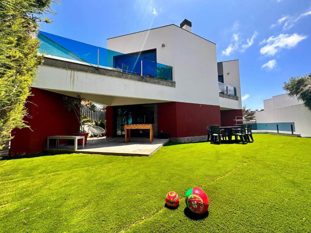 une maison avec une cour avec deux balles sur l'herbe dans l'établissement Palmira Cascais House, à Alcabideche
