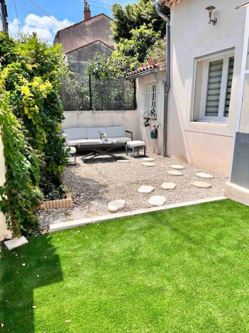 une arrière-cour avec un banc et une pelouse dans l'établissement Petite maison 300m des remparts, Wifi, à Avignon