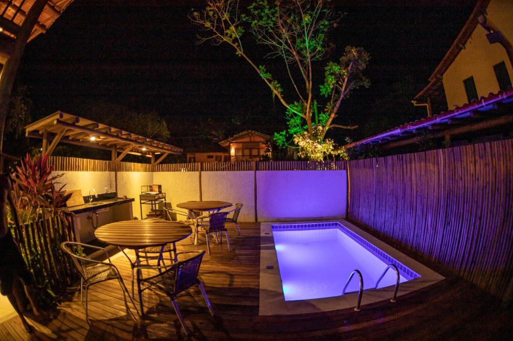 a patio with a table and a swimming pool at night at Flat em Taipu de Fora - Cond Vila Taipu in Barra Grande