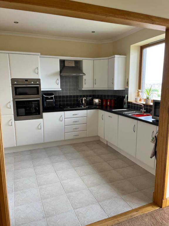 a large kitchen with white cabinets and a window at Apartment 500 - Metro style apartment on NC500 in Thurso