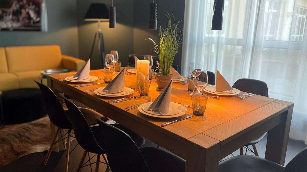 a long wooden table with glasses and napkins on it at InkBlue-Apartment in Heidenau