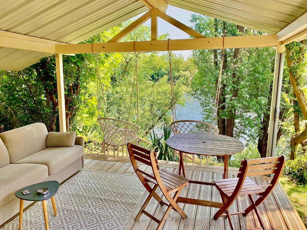 a porch with a couch and a table and chairs at Chalet cosy bord de Seine 30min paris in Carrières-sous-Poissy