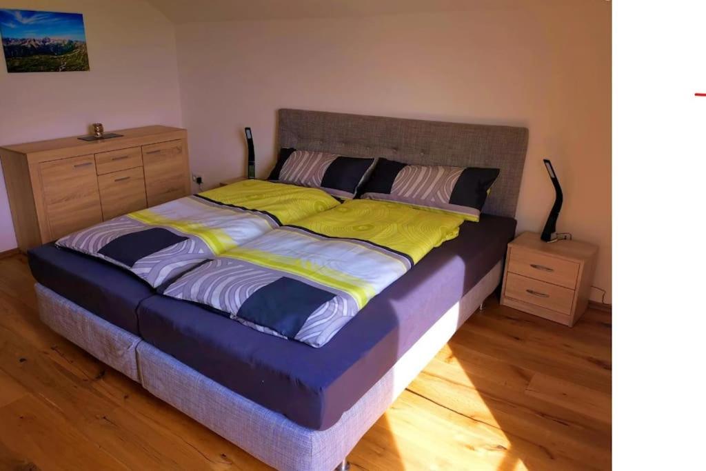 a bedroom with a large bed with yellow and blue sheets at Direkt am Naherholungsgebiet in Marktoberdorf