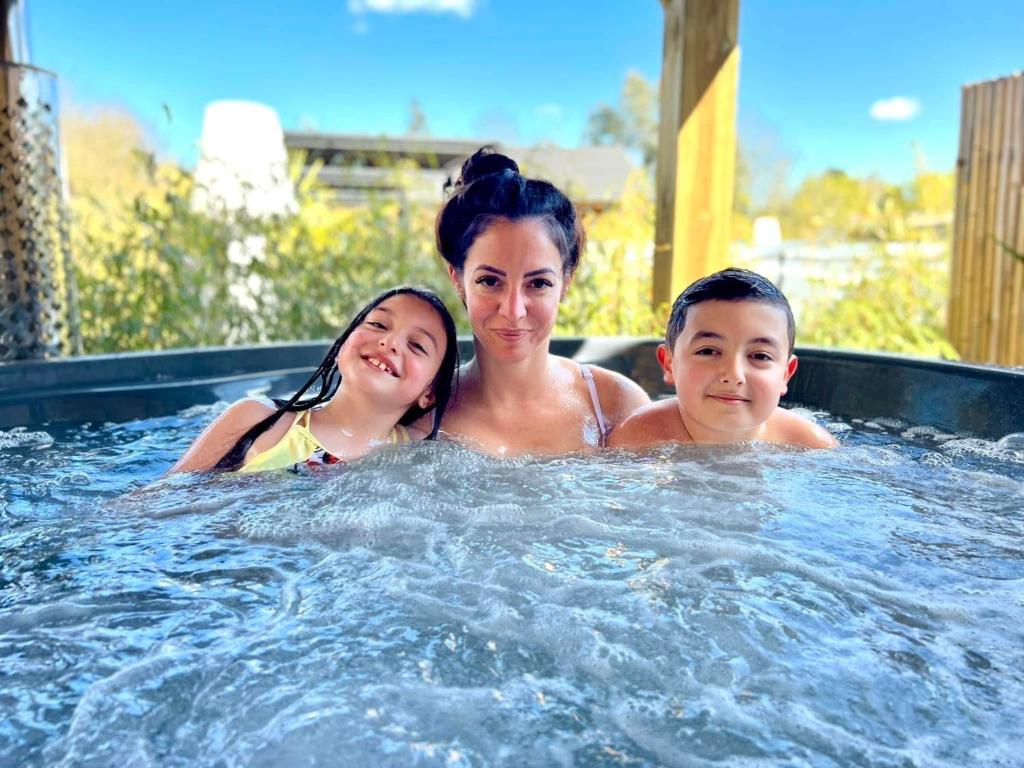 a woman and two children in a hot tub at Gites d'Armor in Treguidel