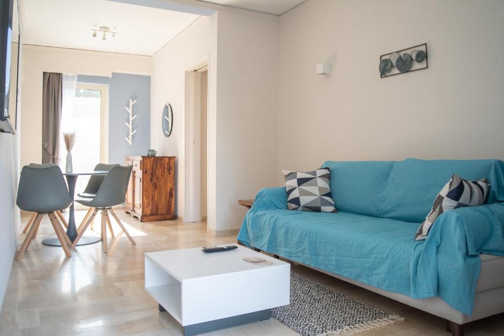 a living room with a blue couch and a table at Naiads Nest - The Blue Wave in Varkiza