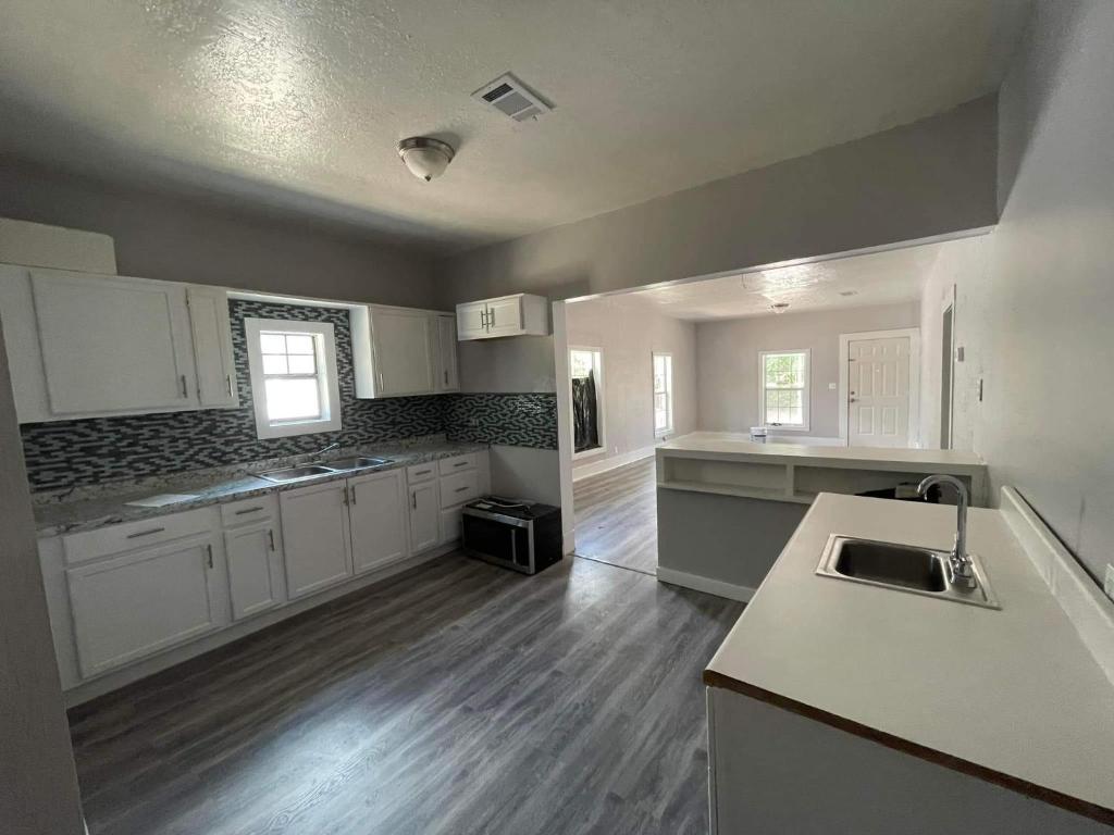 una grande cucina con armadi bianchi e pavimenti in legno di Maple House -Near Lakes a Duncan
