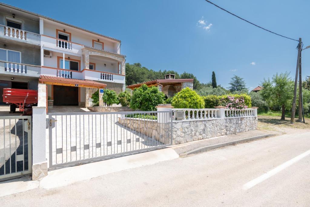 ein Haus mit einem weißen Zaun neben einer Straße in der Unterkunft Apartments with a parking space Mrljane, Pasman - 20056 in Pašman