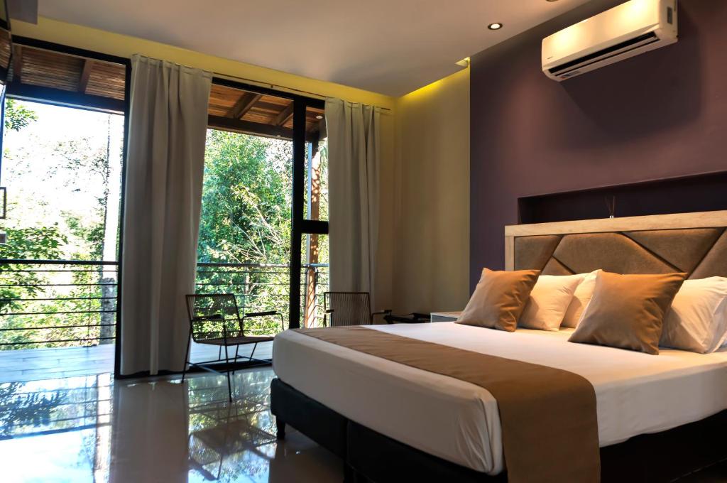 a bedroom with a large bed and a balcony at Tekoa Lodge in Puerto Iguazú