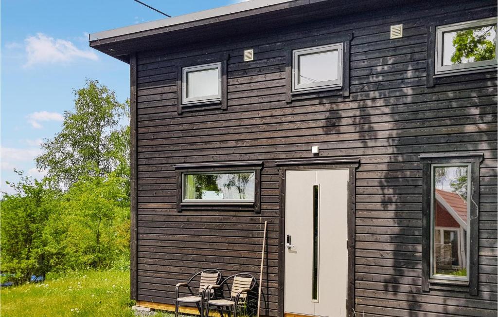 a wooden house with a white door and two chairs at Awesome Home In Trans With Lake View in Tranås