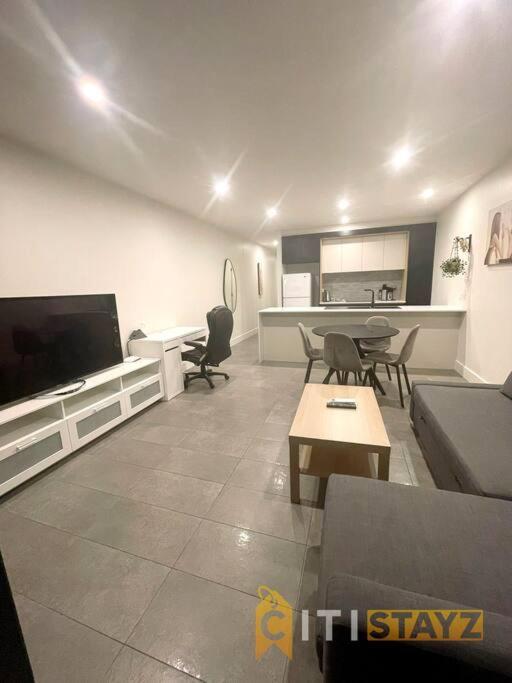 a living room with a couch and a tv at Braddon 1BD - Walk to Cafés, Secure Parking in Canberra