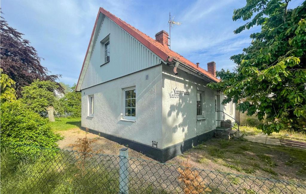 une maison blanche avec un toit rouge et une clôture dans l'établissement Cozy Home In Klagstorp With Kitchen, à Klagstorp