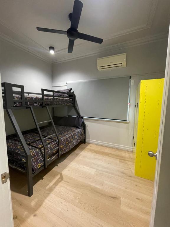 a room with two bunk beds and a ceiling fan at Banana Backpackers in Brisbane