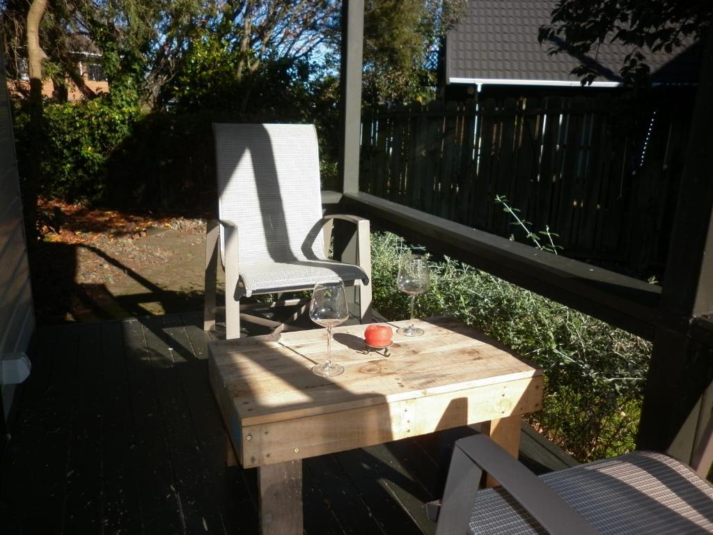 a wooden table with wine glasses and a chair on a porch at A room 5 minutes' walk to the beach in Wellington