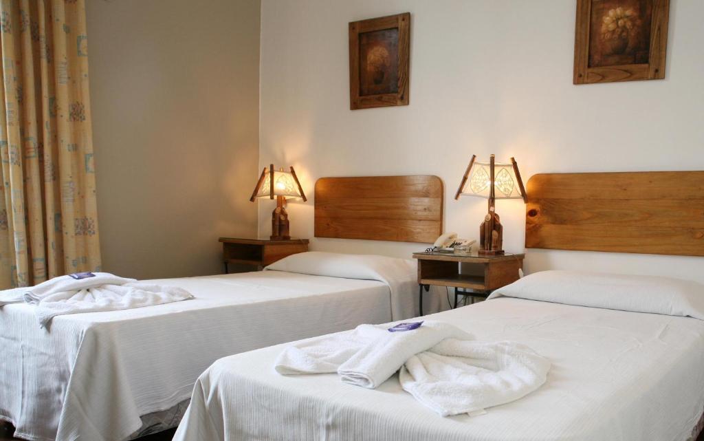 Dos camas en una habitación de hotel con toallas. en Plaza Hotel en Salta