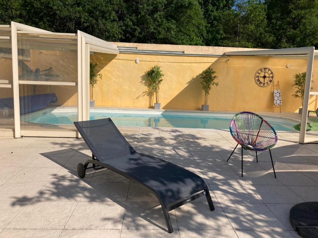 a chair and a racket next to a swimming pool at Chai Saint Jean CAMELIA Piscine et SPA in Saint-Jean-de-Boiseau