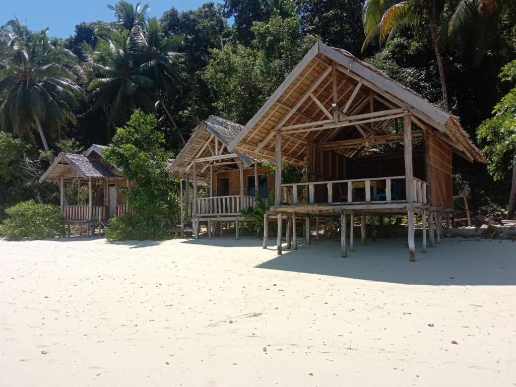 ein Resort an einem Sandstrand mit Palmen in der Unterkunft Amfriwen Homestay in Yennanas Besir