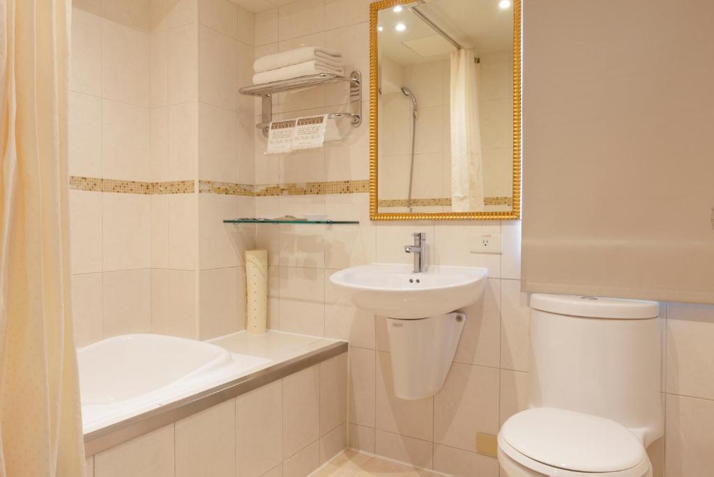 a white bathroom with a sink and a toilet at Shihzuwan Hotel – Kaohsiung Station in Kaohsiung