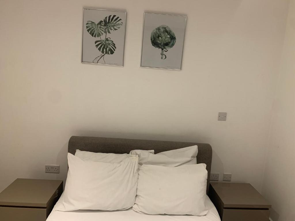 a bed with white pillows and three pictures on the wall at Next to London City airport Apartments in Woolwich