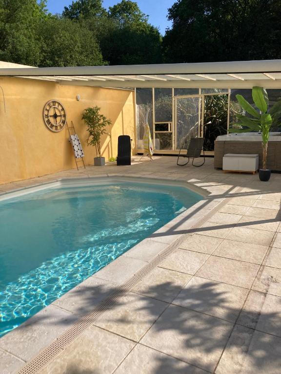 - une piscine dans une terrasse avec une maison dans l'établissement Gîte COQUELICOT F2 avec piscine et SPA, à Saint-Jean-de-Boiseau