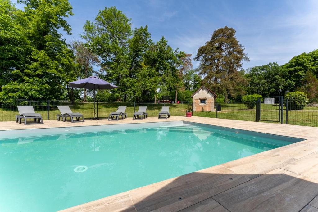 einen Pool mit Stühlen und einem Sonnenschirm in der Unterkunft Gite Cascades du Hérisson 3 chambres piscine in La Châtelaine